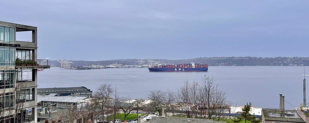 Container ship off the coast of Seattle under cloudy skies.