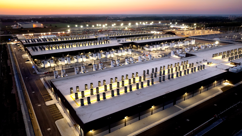 Nighttime aerial photo of Project Rainier, one of the world's largest AI compute clusters. Photo courtesy of <a href="https://www.aboutamazon.com/news/aws/aws-project-rainier-ai-trainium-chips-compute-cluster" target="blank" rel="noopener">Amazon</a>.