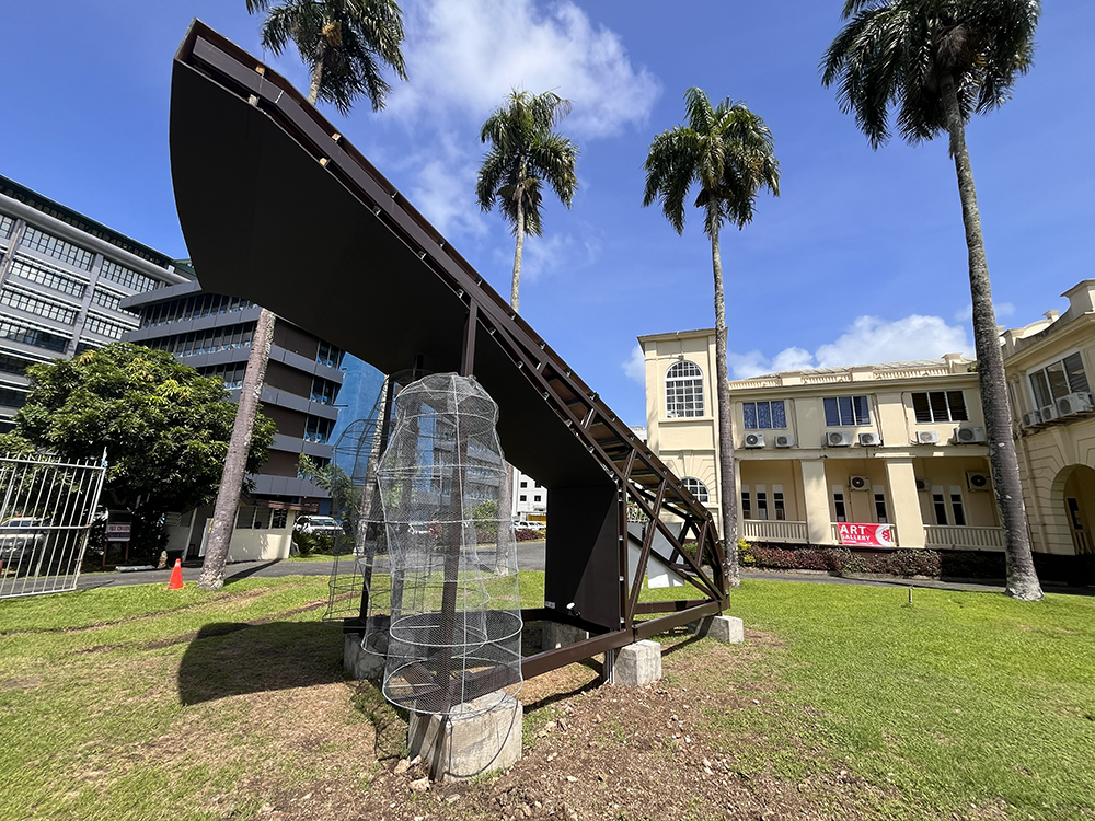 Large prototype shows how the Ligavatuvuce project will be constructed at full scale. Background of palm trees and a yellow colonial building (home to the Fiji Arts Council).