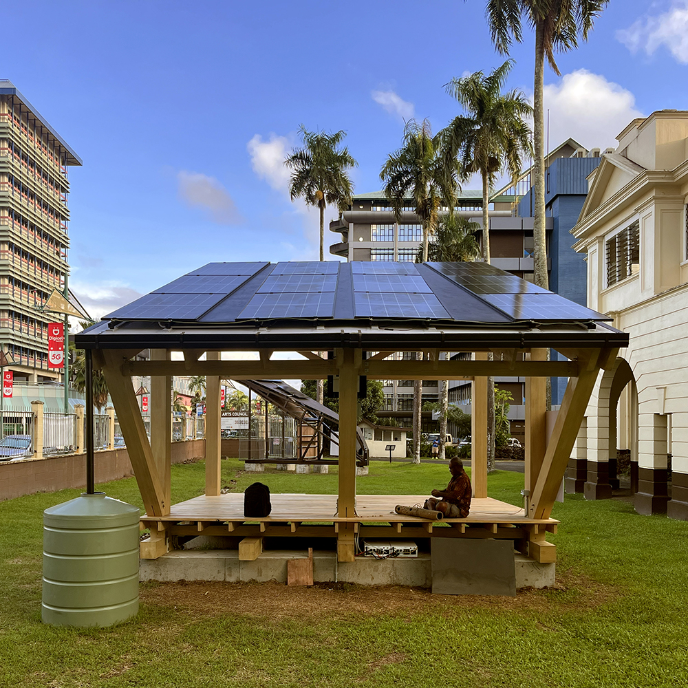 Photo of the built and functioning prototype showing solar panels on the north side. Daytime with just a few fluffy clouds.