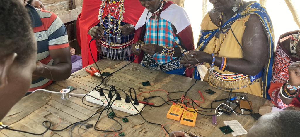 AtasaSolar Partners in Olorgesailie, Kenya wire together the solar modules, charge controllers, power electronics, batteries, and lights. If anything ever breaks the community knows how to diagnose and fix it with locally sourced materials. Lots of wire, electric devices, and soldering equipment on the table.
