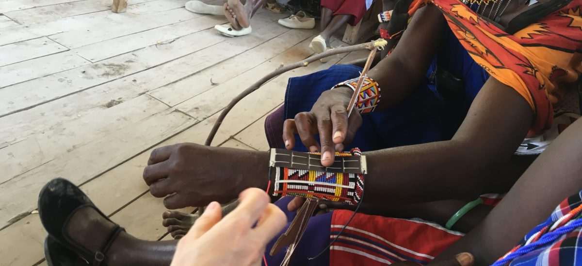 Atasa Solar Maasai women of Olorgesailie Kenya take the lead in designing renewable energy installations for their homesteads. The artisans asked if it was possible to integrate the technology into the items (such as jewelry and belts) that they wear daily. Image of women seated on a bench sharing ideas about beaded bracelets with solar integrated into them.