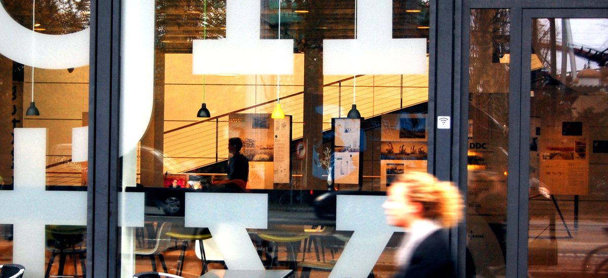 LAGI 2018 Exhibition A LAGI 2014 exhibition in partnership with the Danish Design Center at the Design Society in Copenhagen. View from the street as a bicyclists rides by from right to left. Through the storefront the exhibition can be seen.