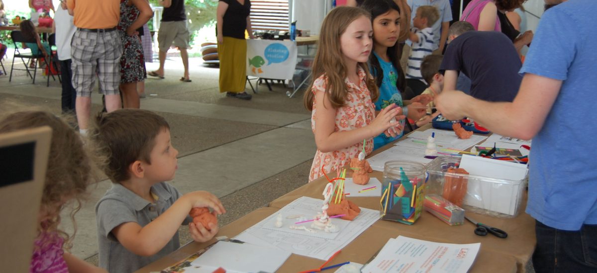 LAGI educational outreach A LAGI workshop for all ages at the Mattress Factory in Pittsburgh. In this photo a group of young kids are on one side of a table at an outdoor event while Robert Ferry explains the LAGI educational games they are engaged in.