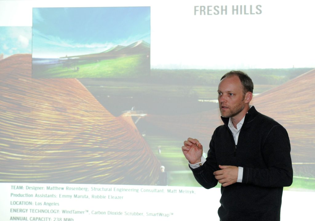 LAGI Director, Robert Ferry giving a presentation in Glasgow, Scotland. Behind him is a projection of "Fresh Kills" by Matthew Rosenberg, a land artwork of organic wood slat forms that integrated wind turbines.