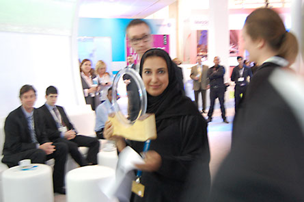 Emirati woman holds the LAGI 2010 prize award prior to handing it to the winning team who is gathered around.